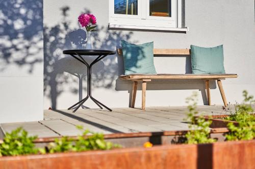 a patio with a bench and a table with a flower on it at Alte Seifensiederei - Rainer Maria in Bad Tölz