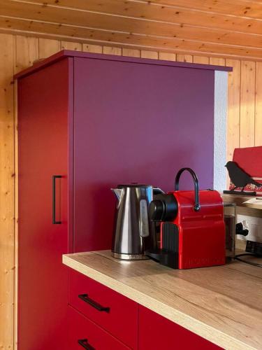 a kitchen with a red cabinet with a tea kettle on a counter at Fougère 11 in Champoussin