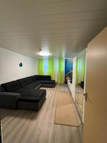 a living room with a black couch and green curtains at Täles Monteur Quartier in Deggingen