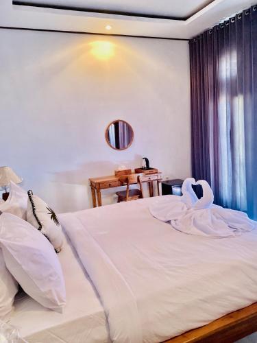 a bedroom with a bed with white sheets and a table at The Luna Cave in Kubupenlokan