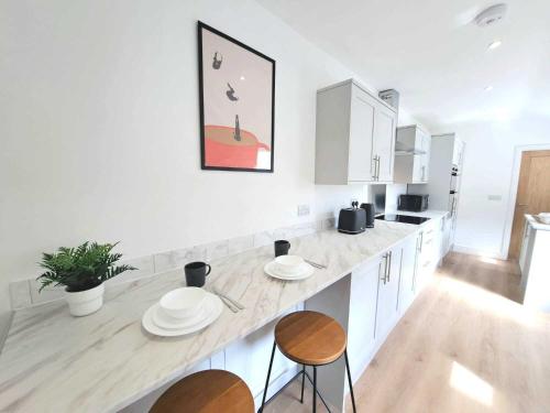 a white kitchen with two chairs and a counter top at Modern Newly Refurbished 3-Bedroom House in Lincoln