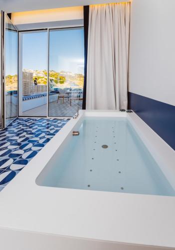 a room with a bathtub and a large window at Hotel La Roccia in Castro di Lecce