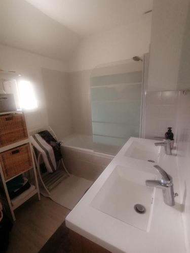 une salle de bain blanche avec un lavabo et une baignoire dans l'établissement Maison paisible 3 chambres proche parc expo, à Chartres-de-Bretagne