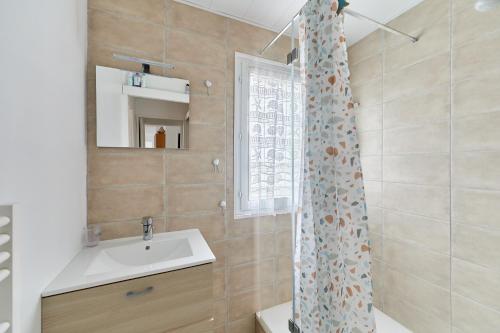 une salle de bain avec un lavabo et un rideau de douche dans l'établissement Le Repos de Cabourg - Appt à 650m de la plage, à Cabourg