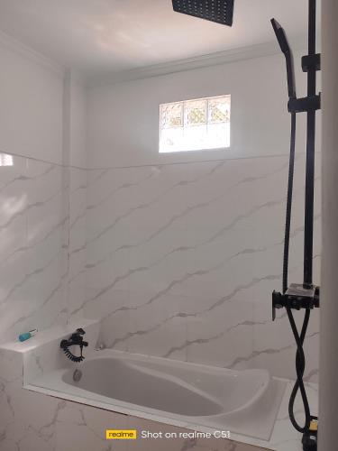 a white bathroom with a tub and a window at Wiwik sweet villa in Amed