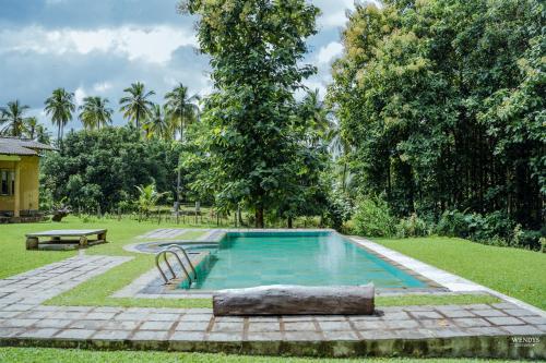 a pool in a yard with a bench and trees at Rivendell Twisted Tree in Kurunegala