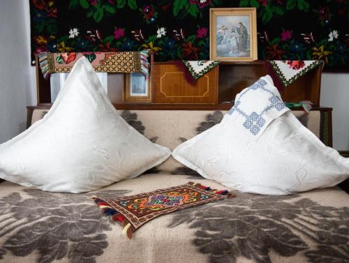 two pillows sitting on top of a bed at Casuta bunicilor in Volovăţ