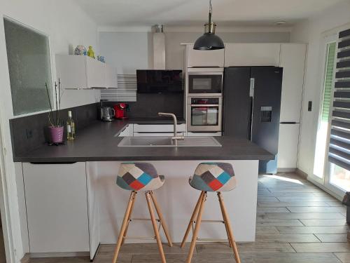 une cuisine avec un évier et un comptoir avec deux tabourets dans l'établissement Appart à 15 minutes de la plage, à Perpignan