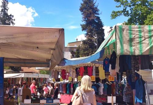 a woman walking past a market with clothes on display at Casa alla Cascata in Cunardo