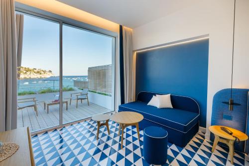 a hotel room with a blue couch and a balcony at Hotel La Roccia in Castro di Lecce
