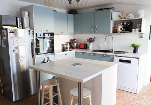 une cuisine avec des placards bleus et un comptoir avec des tabourets dans l'établissement Maison familiale 4 chambres, au coeur de Loix, location à la semaine UNIQUEMENT, à Loix