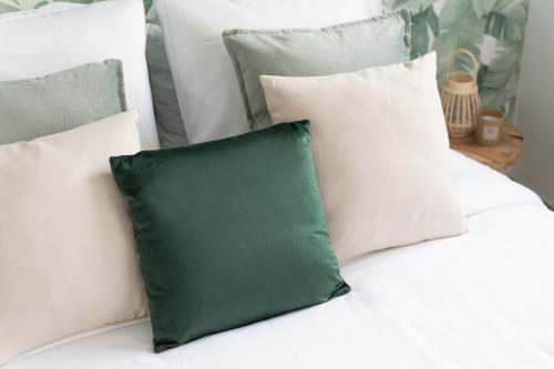 a green pillow sitting on a white couch with pillows at Appartement - 4 personnes - Parking Privé - Métro 7 - Rer B in La Courneuve
