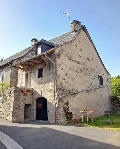 - un ancien bâtiment en pierre avec une table devant dans l'établissement Maison de village du Carriérou, à Montézic