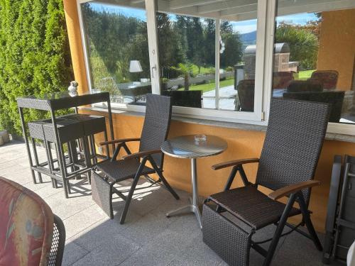 a porch with four chairs and a table and a window at Residenza San Remy in Unterkulm