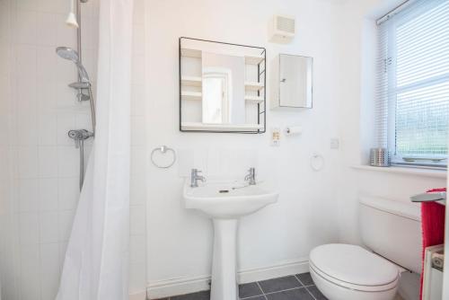 a white bathroom with a sink and a toilet at Chestnutt Cottage, Reydon in Reydon