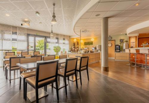 a restaurant with a table and chairs and a kitchen at B&B HOTEL Calais Terminal Cité Europe 4 étoiles in Coquelles