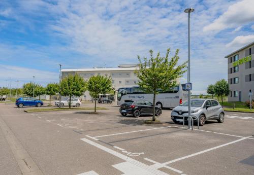 a parking lot with cars parked in front of a building at B&B HOTEL Calais Terminal Cité Europe 4 étoiles in Coquelles