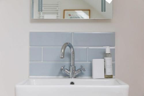 a sink with a faucet in a white kitchen at Pretty Coastal Home in Bosham Close to Water in Bosham