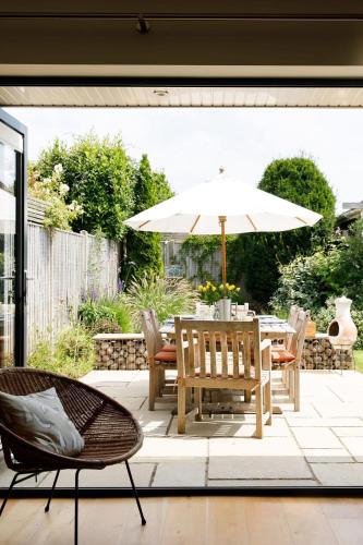a patio with a table with an umbrella and chairs at Pretty Coastal Home in Bosham Close to Water in Bosham