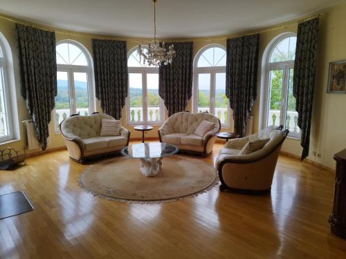 a living room with chairs and a table and windows at Kuća za odmor Sunce in Kraljev Vrh