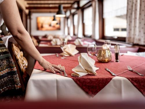 a table with a red table cloth and forks and napkins at Hotel Engel in Mellau