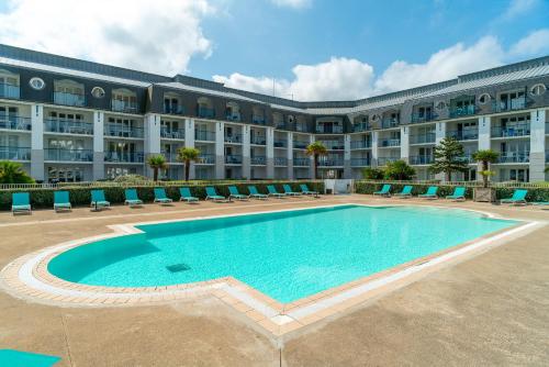 une piscine en face d'un grand bâtiment dans l'établissement Le Tamm Bara - Appt avec piscine partagée, à Douarnenez
