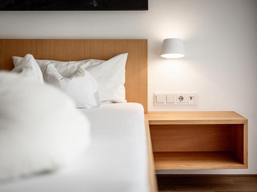 a bed with white pillows and a wooden head board at Hotel Engel in Mellau