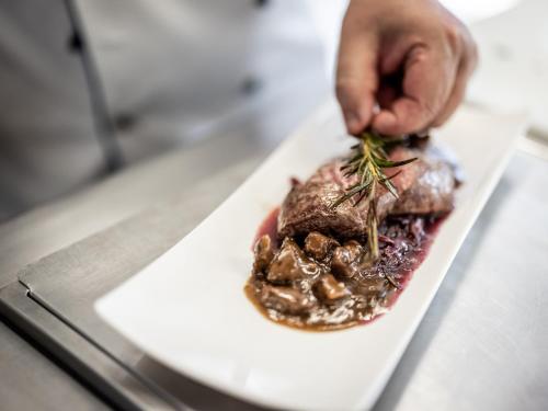 a person eating a dish on a white plate at Hotel Engel in Mellau
