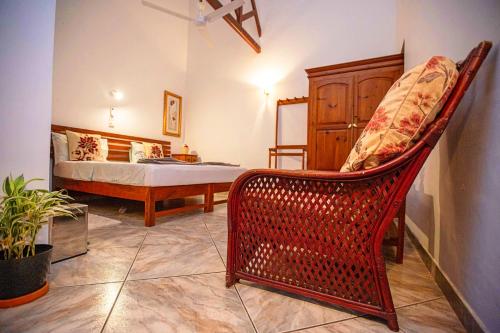 a bedroom with a wicker chair and a bed at Arcadia Resort in Hikkaduwa