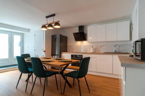 une cuisine avec une table en bois et des chaises vertes dans l'établissement L'Écrin d'Hennebont - Maison en pierre pour 8, à Hennebont