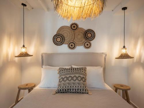 a bedroom with a bed with two stools and three lights at Katinas atelier in Kampos Paros