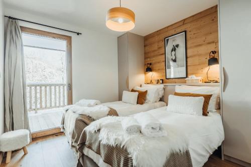 a bedroom with three beds and a window at Le Cocon Blanc - Appartement « cosy & chic » in Megève