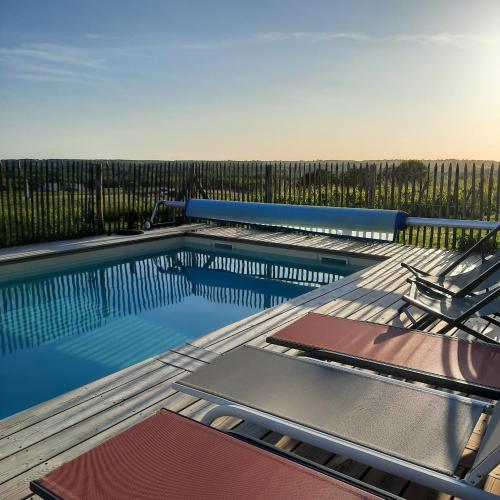 une piscine avec deux chaises et une clôture dans l'établissement Le Castèl de Lamothe, à Sauternes