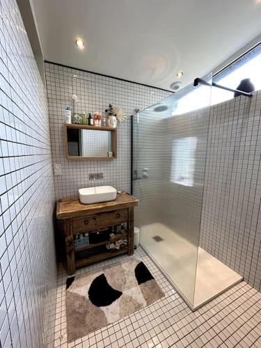 une salle de bain avec une douche en verre et un lavabo dans l'établissement Jolie Maison a l Ocean, à Lacanau