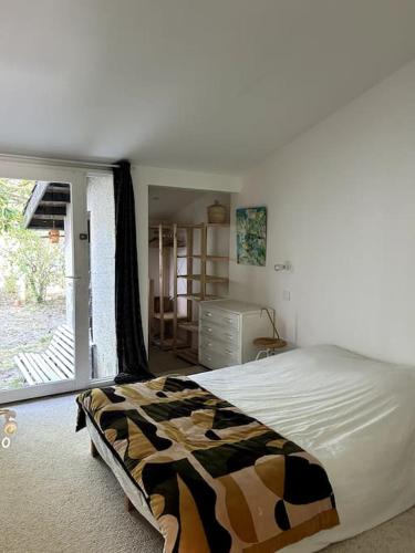 une chambre avec un lit et une grande fenêtre dans l'établissement Jolie Maison a l Ocean, à Lacanau