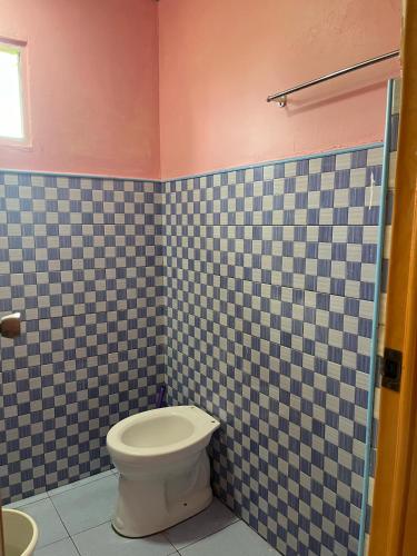 a bathroom with a toilet and a tiled wall at Zia's homestay-2 in Siquijor