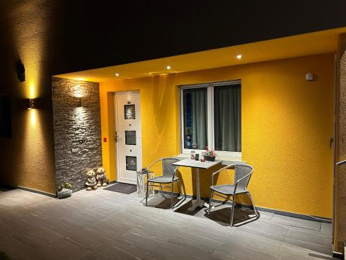 a patio with a table and chairs and a yellow wall at Residenza San Remy in Unterkulm