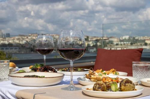 a table with two glasses of wine and food at Istanbul Old City Colorful Houses Balat PETRION Hotel in Istanbul