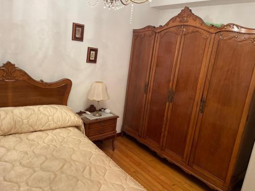 a bedroom with a large wooden cabinet next to a bed at Acogedora casa a pie de playa in Cillero