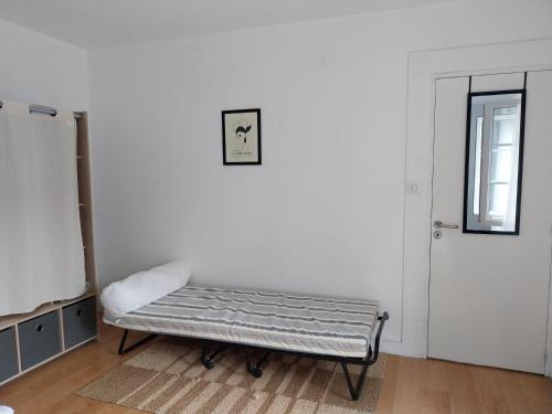 une chambre blanche avec un banc devant une porte dans l'établissement Chez Colette, à Montviron