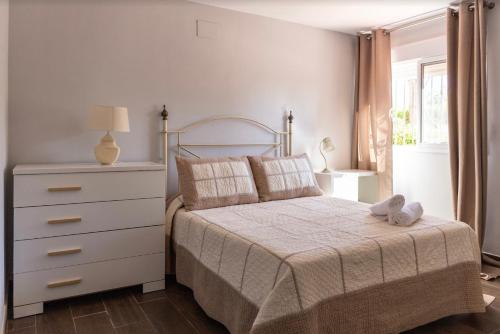 una camera con letto bianco, cassettiera e finestra di Casa Rural Sevilla a Guillena