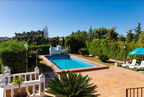 una piscina in un cortile con sedie e ombrellone di Casa Rural Sevilla a Guillena