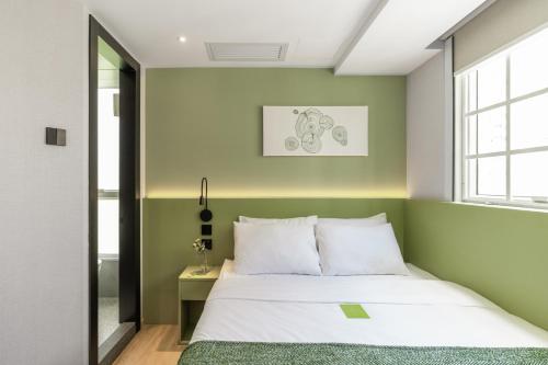 a bedroom with green and white walls and a bed at Urbanwood Hung Hom in Hong Kong