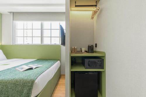 a small room with a bed and a microwave at Urbanwood Hung Hom in Hong Kong