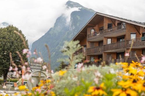 a building with a mountain in the background with flowers at Charmant appartement avec balcon et commodités modernes in Samoëns