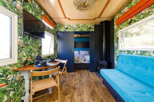 a tiny house with a blue couch and a table at The Showman's Carriage w King Bed close to beach in Birdham