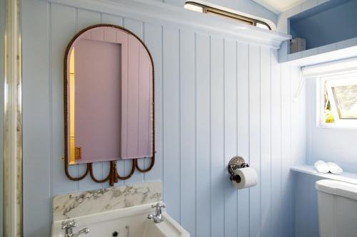 a bathroom with a mirror and a sink and a tub at The Showman's Carriage w King Bed close to beach in Birdham