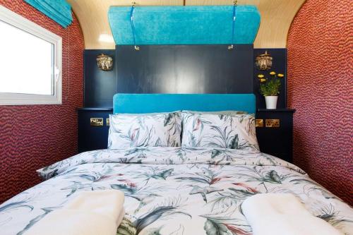 a bedroom with a bed with a blue headboard at The Showman's Carriage w King Bed close to beach in Birdham