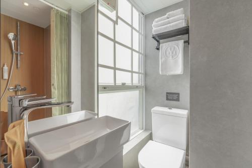 a bathroom with a sink and a toilet and a window at Urbanwood Hung Hom in Hong Kong