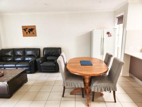 a kitchen with a table and chairs and a couch at Cosy Family Retreat in Truganina in Truganina